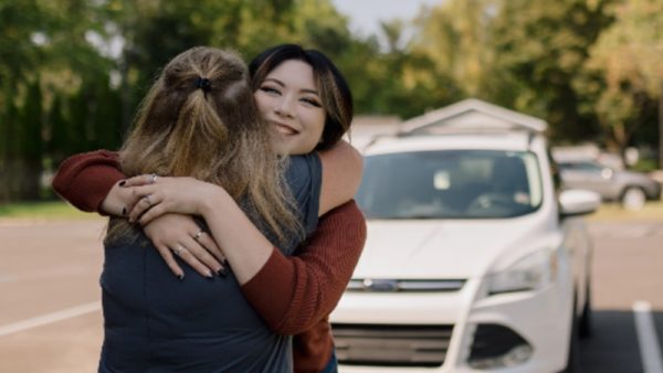 Kadence hugs a Lake Trust Credit Union branch staff as they celebrate her recent car purchase.
