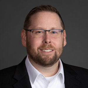 Headshot of Paul Kirkbride, COO at Washington State Employees Credit Union, wearing glasses, a dark jacket, and a white shirt against a neutral background.